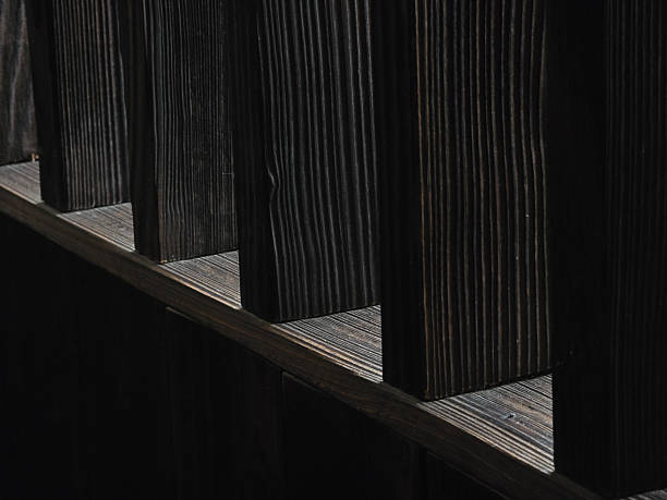 Dark wooden planks create striking contrast with light, showcasing texture and depth. interplay of shadows adds dramatic effect to composition