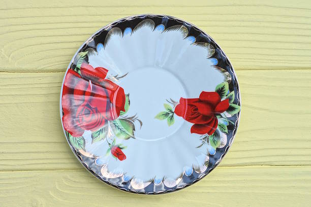 one white empty ceramic plate with a pattern of red flowers stands on a yellow table