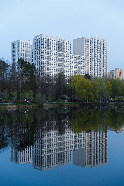 istock Modern Residential Complex Reflected in a Serene Lake Surrounded by Lush Greenery and Urban Life at Dusk, Showcasing Contemporary Architecture in Harmony with Nature 2227562680