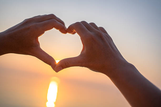 istock Shape of hearts with hands in sunset 2227564475