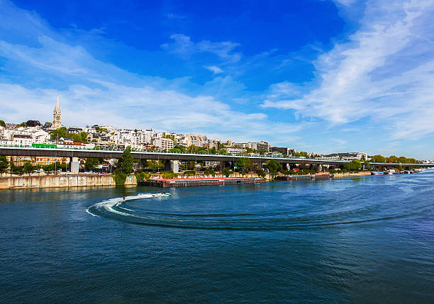 Water skiing behind a boat in Paris on a sunny day.  District by viaduc de Saint-Claud  (blurrred motion people)
