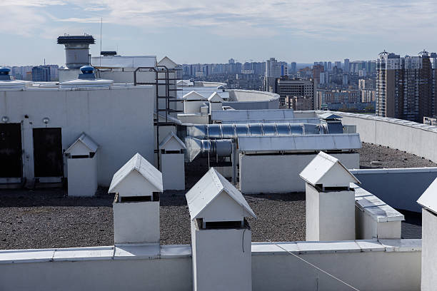 istock Urban Rooftop View Featuring White Architectural Structures Against a City Skyline with High-Rise Buildings Under a Clear Blue Sky and Soft Clouds 2227564817