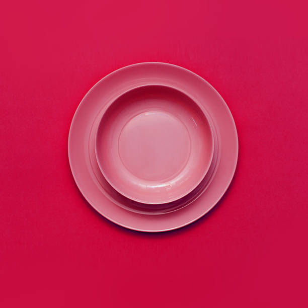 istock Red round deep plate stands on a flat plate against a red color background. 2227568234