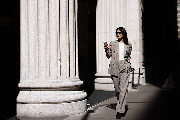istock Businesswoman walking and using smartphone next to columns 2227571912