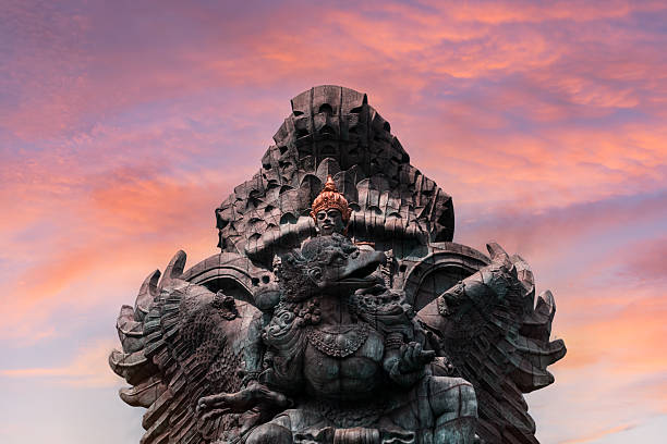 Majestic Garuda Wisnu Kencana statue in Bali, Indonesia, captured at sunset with vibrant pink and orange sky backdrop.