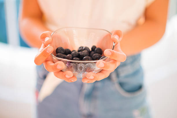 A collection of freshly picked blueberries being held in cupped hands under soft sunlight, evoking feelings of natural health, organic living, and wholesome nourishment.