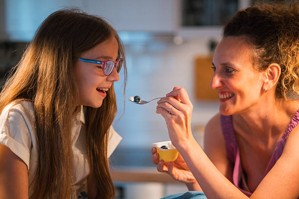 istock Mother Feeding Daughter Blueberries in Brightly Lit Kitchen Setting 2227578827