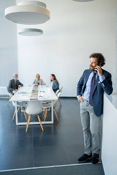 istock Businessman talking on phone while colleagues having meeting 2227579134
