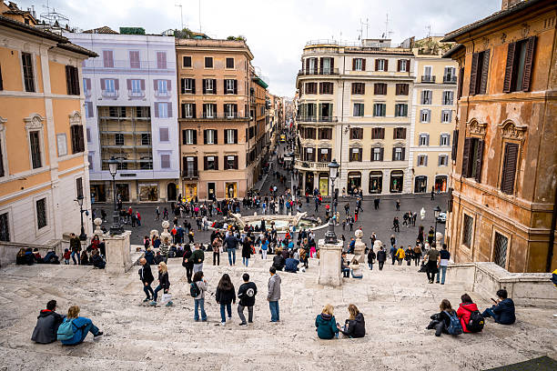 Rome, Italy - March 10, 2023: Tourists relaxing and soaking in the stunning views from the Spanish steps in Piazza di Spagna, experiencing the vibrant atmosphere of Rome