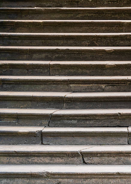 Close up of old stone steps with cracks and weathered texture. Ideal as background or texture for design, architecture, history, or vintage themed projects.