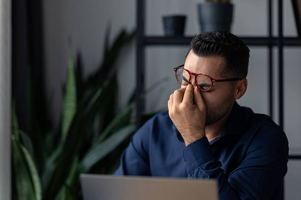 istock Tired businessman rubbing his eyes while working on a laptop, suffering from eye strain or a headache 2227593257