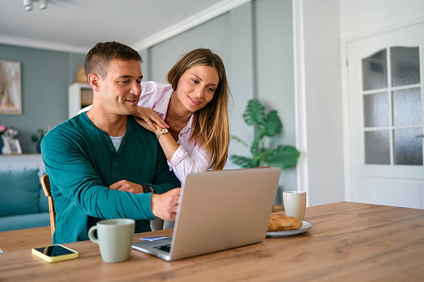istock Couple using laptop together at home, browsing internet and smiling 2227594816