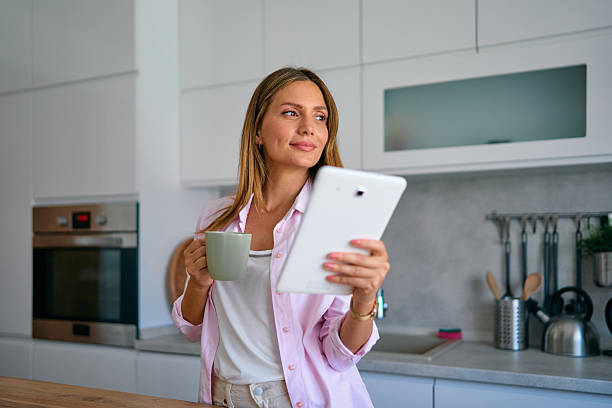 istock Woman enjoying morning coffee and using digital tablet in kitchen 2227594958