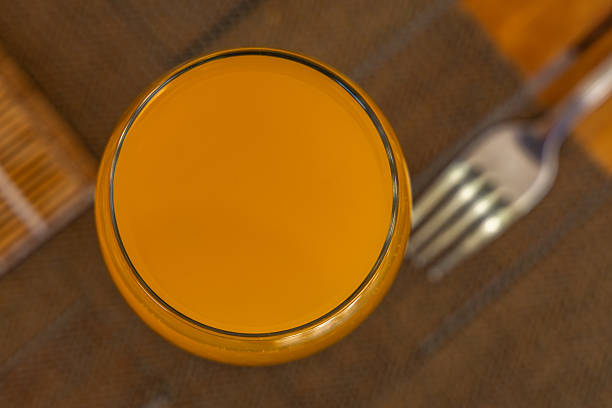 Orange juice poured into a glass placed on the table, a refreshing carbonated drink in a glass