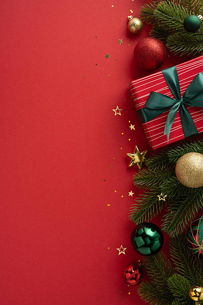 istock Seasonal holiday vertical image showing a gift box surrounded by ornaments and pine branches on a red background, emphasizing the joyful Christmas theme and festive spirits 2227600309