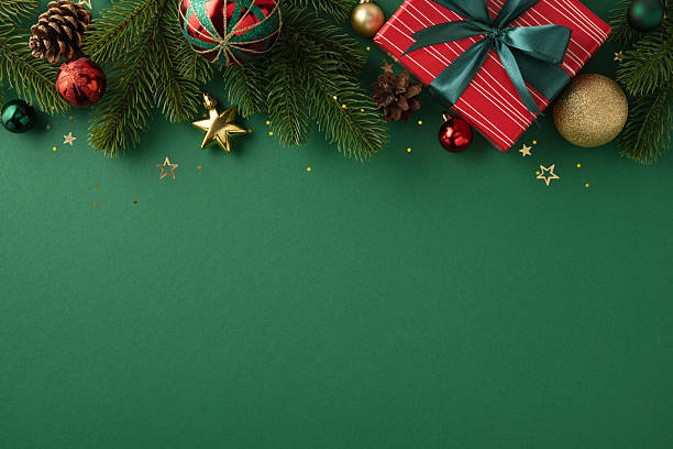 Holiday-themed composition featuring ornaments, evergreen branches, and a wrapped gift box on green background, conveying a festive, celebratory atmosphere