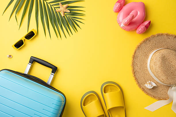 istock Flat lay composition featuring a suitcase, hat, sunglasses, and swim items on yellow. Vibrant summer theme 2227600341