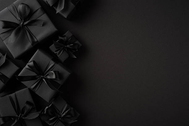 istock Dark gift boxes with black satin ribbons artfully arranged on a moody, minimalistic backdrop creating a sophisticated atmosphere. 2227600372