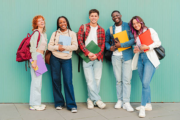 istock Enthusiastic group of friendly students standing together with notebooks and folders, exuding joy as they celebrate their academic journey and the bonds of friendship formed during their studies 2227601107