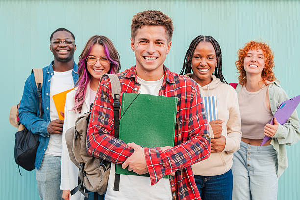 istock Group Of Joyful Young Students Smiling Together While Holding Books And Notebooks In Their Hands on a turquoise background , Celebrating Their Achievements And Friendship In A Lively High School 2227601312