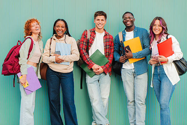 istock Cheerful diverse group of students smiling and holding colorful notebooks while enjoying their time together on campus during a sunny day surrounded by the joy of learning and friendship 2227602101