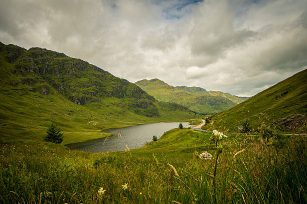 A panoramic view on Loch in the valley and mountains surrounding the loch from the viewpoint, cloudy day