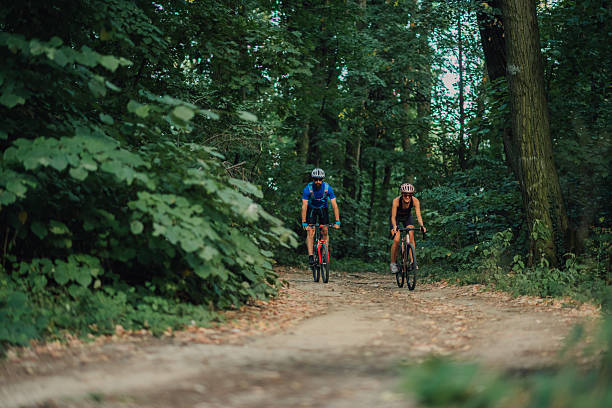 istock Couple cycling on gravel path through lush forest 2227606644