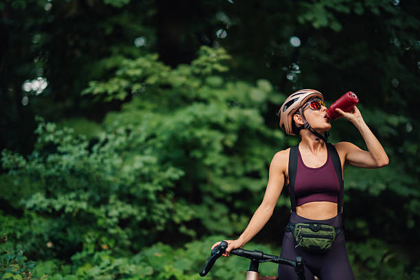 istock Female cyclist refreshing with a drink in the woods 2227606646