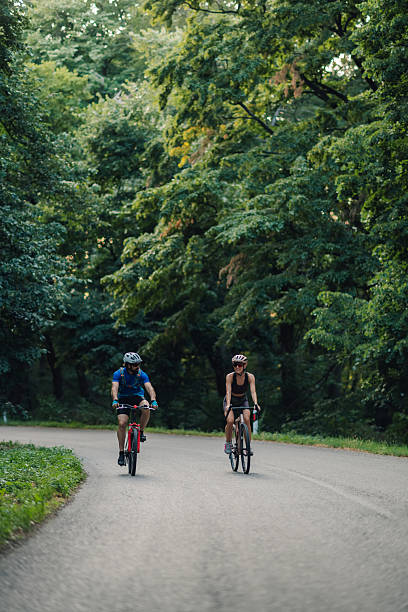 istock Couple cycling on a road through green forest 2227606657