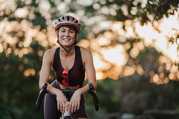 istock Smiling female cyclist resting on bicycle in park at sunset 2227606770