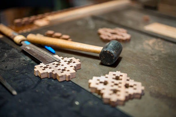 Close-up photograph of intricate wooden geometric patterns and traditional woodworking hammer on textured dark workshop surface, highlighting detailed Islamic mashrabiya craftsmanship.
