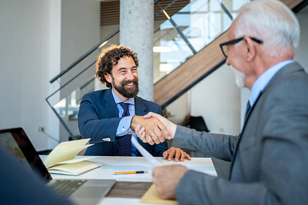 istock Two businessmen shaking hands after signing contract in modern office 2227611438