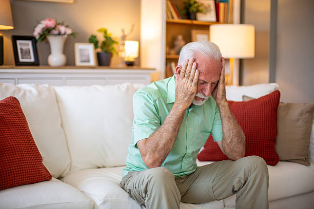 istock Senior man suffering from headache while sitting on sofa at home 2227611644