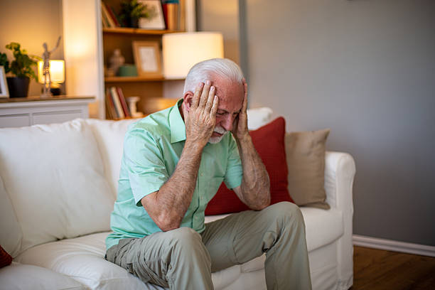 istock Senior man suffering from headache while sitting on sofa at home 2227611662