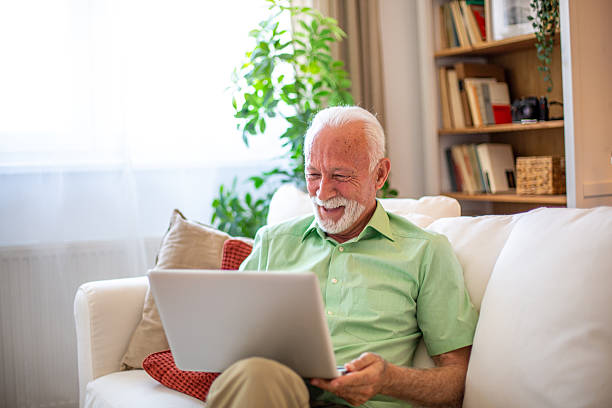 istock Senior man relaxing on sofa using laptop at home 2227611917