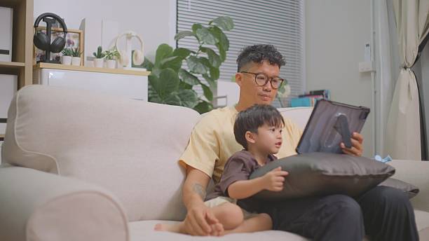 istock Asian Father Feeding Son While Watching Tablet Together. 4k 2227612393