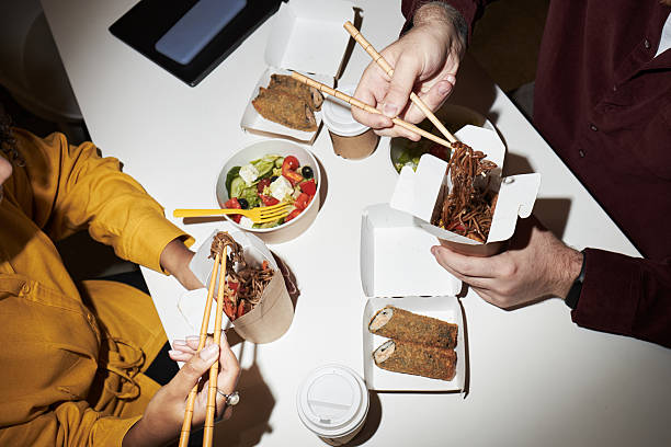 Multiethnic Colleagues Sharing Takeout Noodles and Salad during Lunch Break
