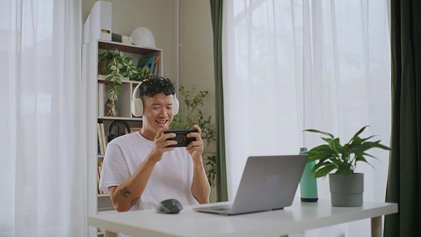 istock Asian Man Taking a Break from Work to Play Mobile Games. 2227614295