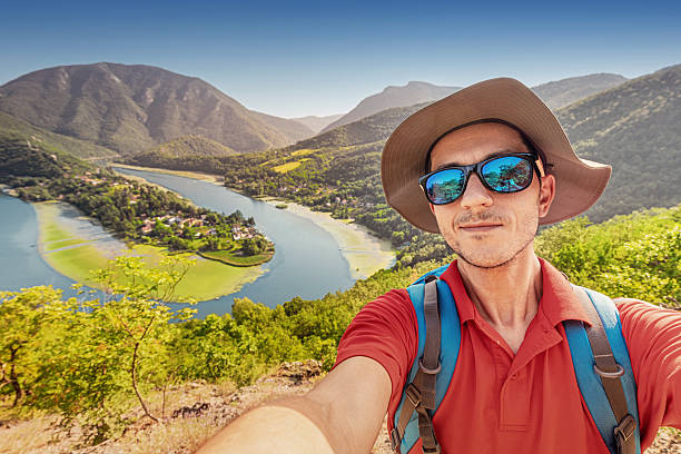 Hiker capturing a joyful selfie against a stunning summer landscape, featuring mountains and Morava river in Ovcar Kablar gorge, Serbia
