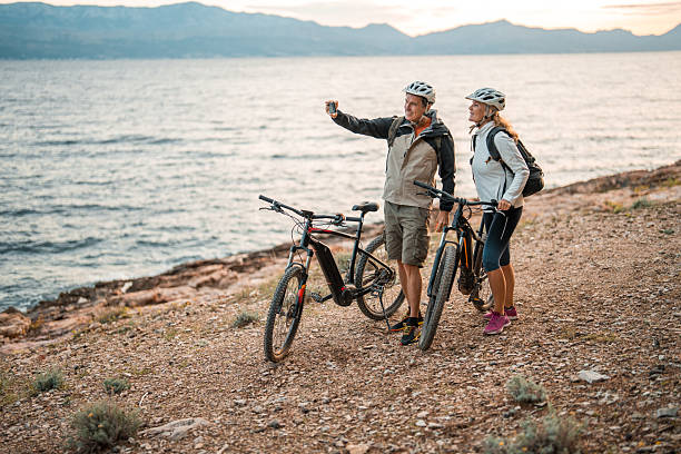 istock Active Senior Couple with Electric Bikes Taking Selfie at Seaside Dawn 2227617845
