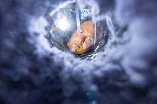 istock man is looking through one end of a dryer vent with a flashlight 2227619738