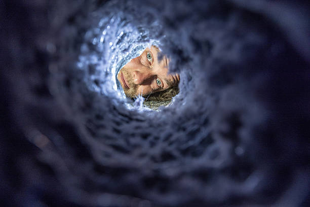 istock man is looking through one end of a dryer vent with a flashlight 2227619907