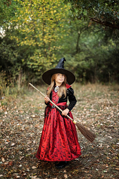 Portrait of a young woman dressed like an evil witch and practicing magic in the forest.