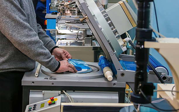 istock Worker operates machinery for packaging blue plastic materials in a factory setting during daylight hours 2227631714