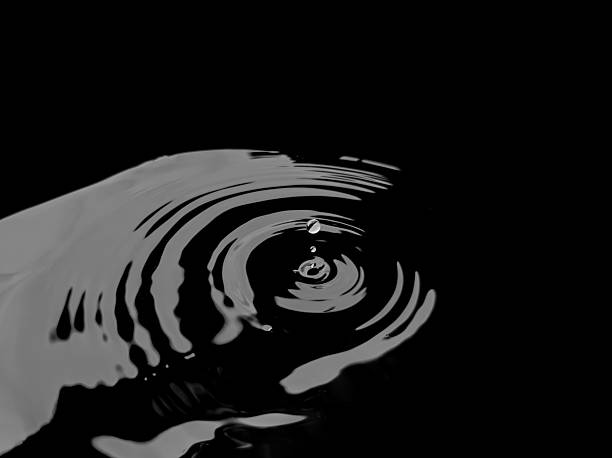 Black and white art image of water drops hitting the water surface, creating beautiful circular ripples, reflecting simplicity and stillness.