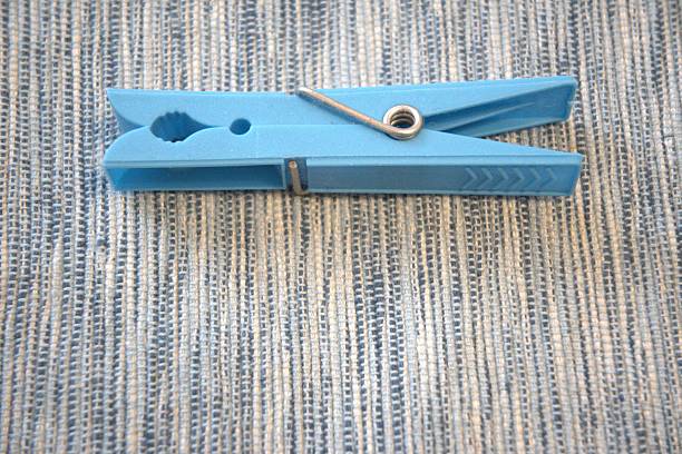 Close-up of a single blue plastic clothespin lying on blue fabric. Tonal color harmony with minimalist composition and space for text.