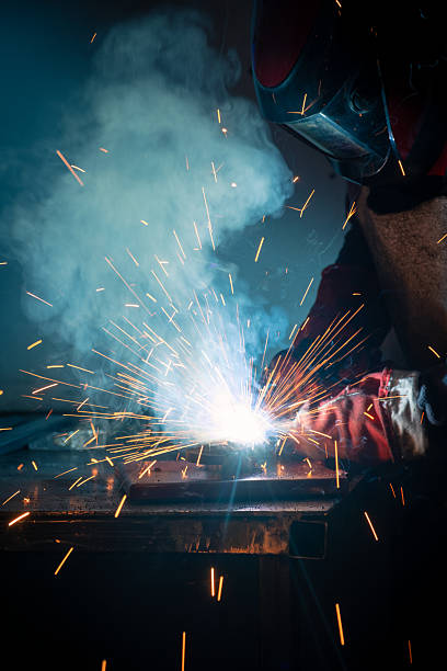 istock Welder using specialized equipment to join metal structures, generating bright sparks and smoke in a dark environment 2227639535