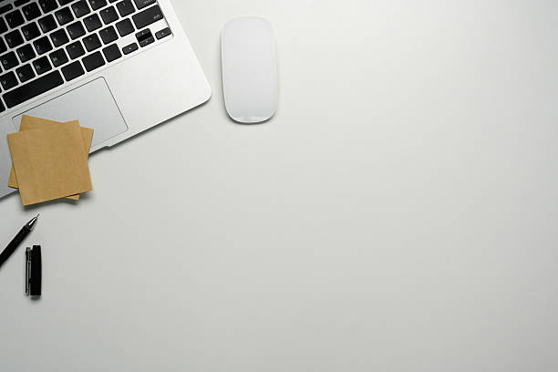 Minimalist workspace with laptop, wireless mouse, and sticky notes on a clean white desk.