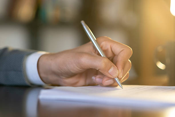 istock Businessman is taking notes on a paper sheet using a pen in his office 2227640634