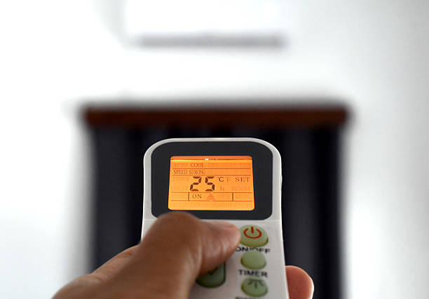istock Air conditioner with remote control being pressing by woman hand. 2227643820